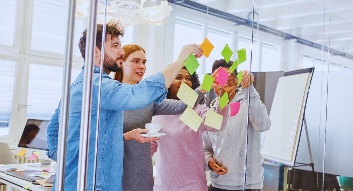 Équipe en atelier de brainstorming avec post-its colorés sur vitre