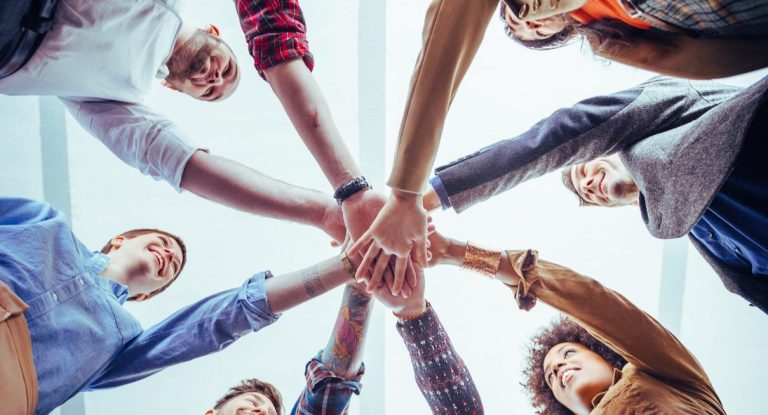 groupe de jeunes professionnels qui joignent leurs mains en cercle pour illustrer l'esprit d'équipe
