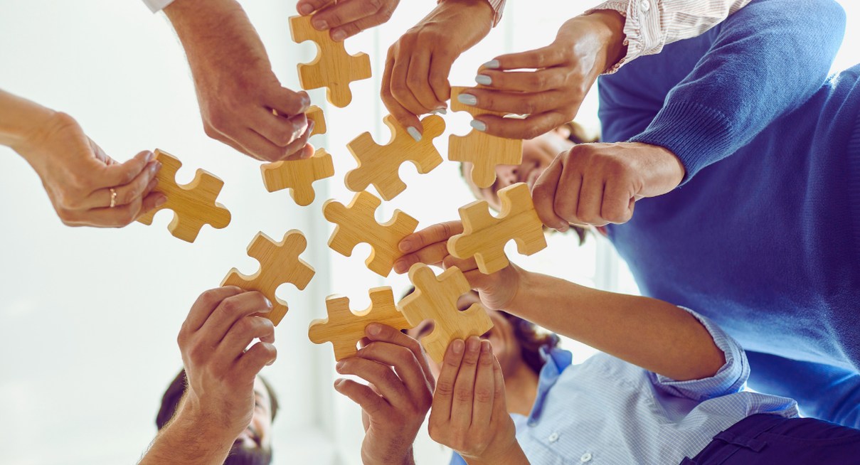 Mains de collègues tenant des pièces de puzzle lors d'un exercice de cohésion d'équipe