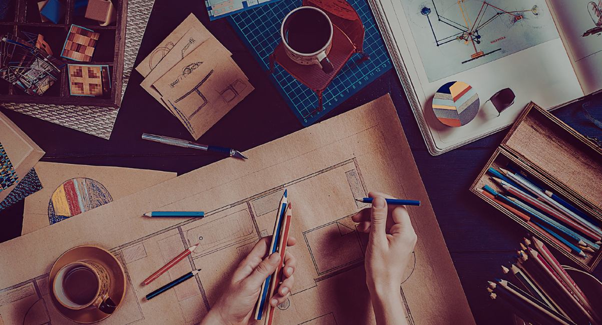 Mains dessinant sur des plans dans un espace de travail créatif avec crayons
