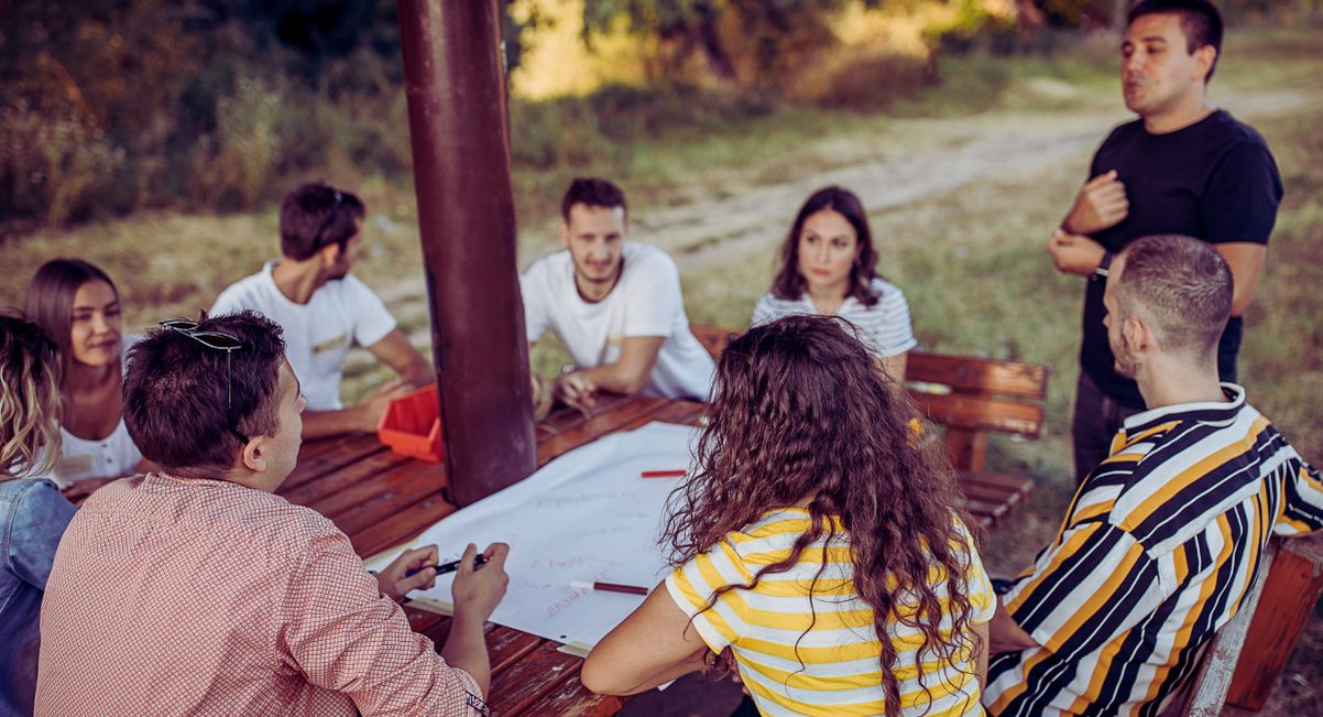 Groupe de jeunes en réunion team building autour d'une table en plein air