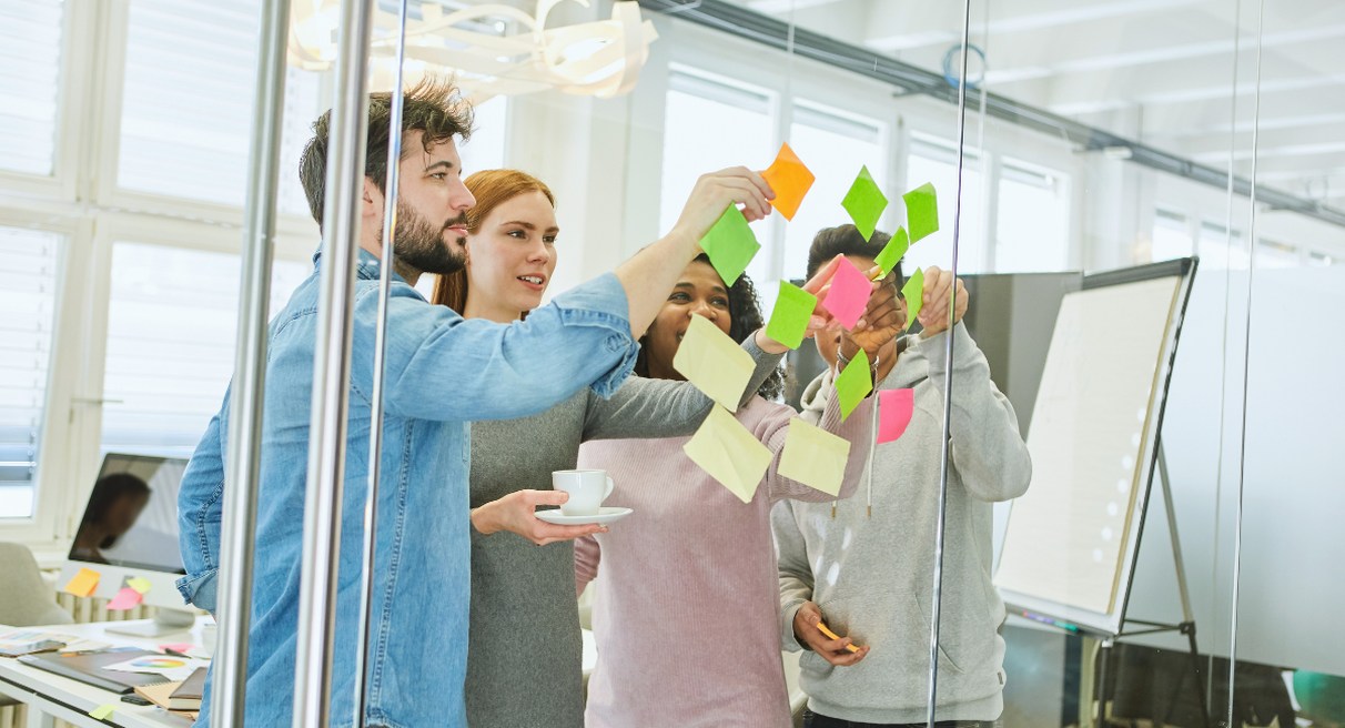 Equipe collant des post-it colores sur une paroi vitree lors d'un atelier de lancement