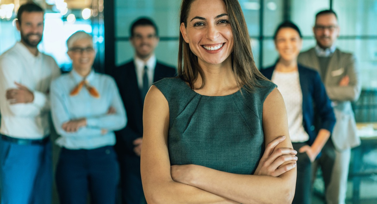 Femme leader d'equipe debout souriante avec ses collegues derriere elle