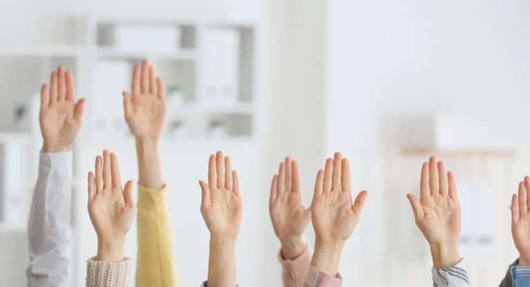 Plusieurs personnes levant la main en meme temps pour voter en groupe